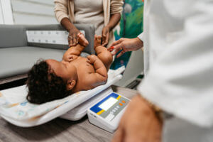 Female Pediatrician Weighing A Baby Boy at wellness checkup center